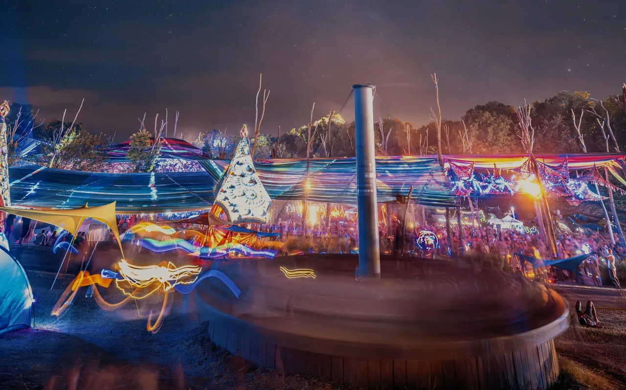 Une scène de festival psytrance de nuit sous la Voie lactée